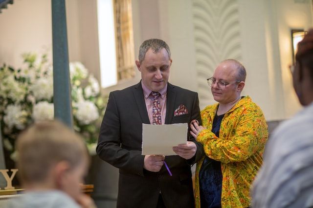 a man in a suit is holding a piece of paper while standing next to a woman in a yellow jacket .