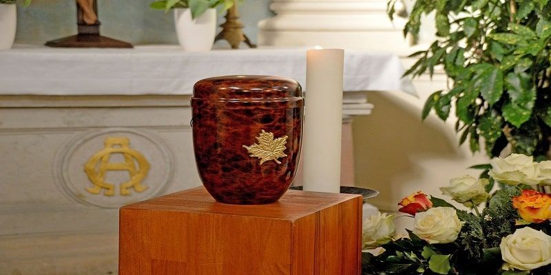 a urn is sitting on a wooden block in front of a candle in a church .