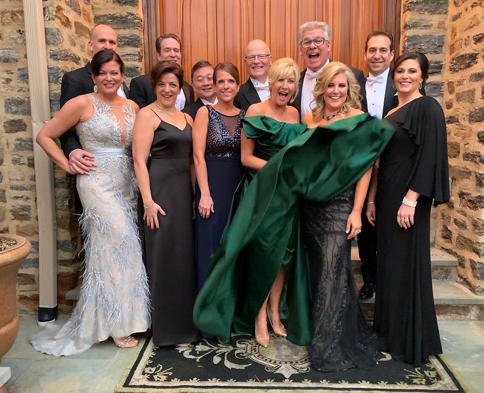 A group of people posing for a picture with one woman wearing a green dress