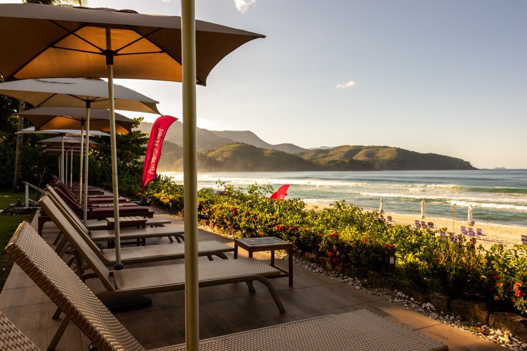 Uma praia com cadeiras e guarda-sóis e vista para o oceano.