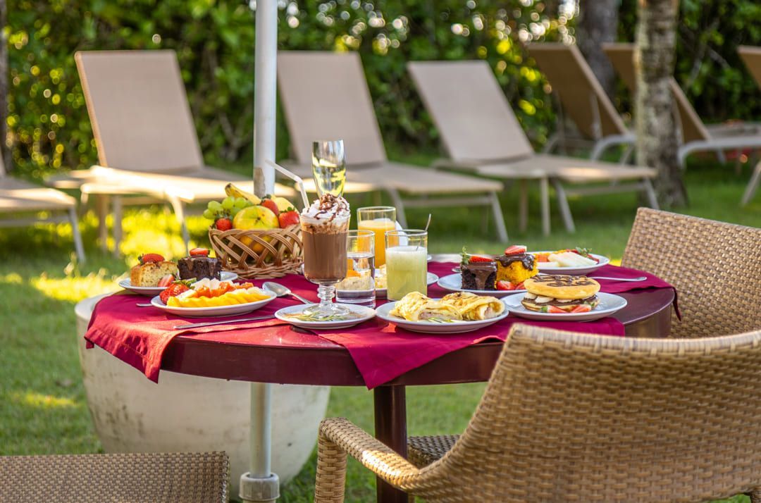 Uma mesa com pratos de comida e bebidas em um jardim.