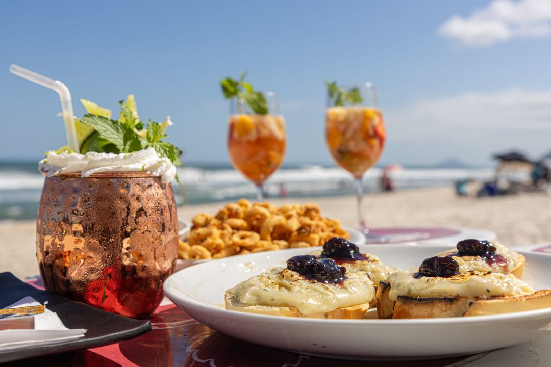 Um prato de comida e duas taças de vinho em uma mesa na praia.