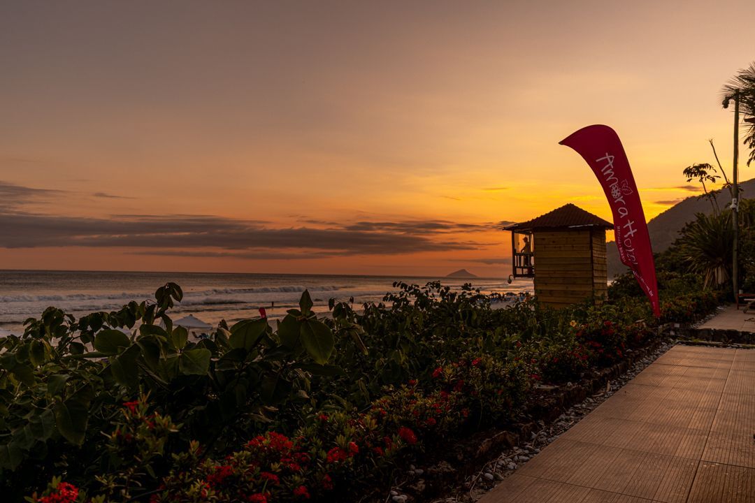 Um pôr do sol sobre o oceano com uma torre de salva-vidas em primeiro plano.