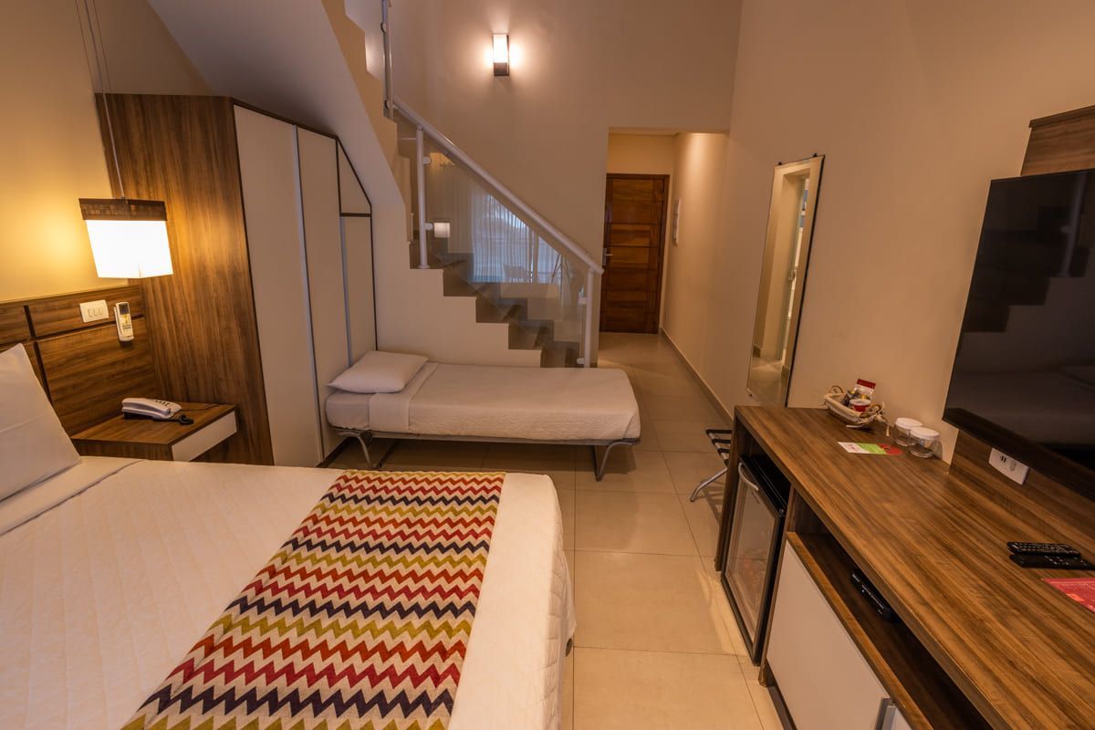 Um quarto de hotel com uma cama, televisão e escadas.