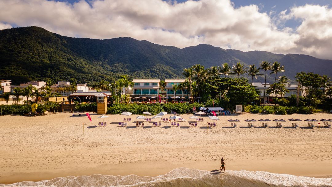 Uma vista aérea de uma praia com montanhas ao fundo.