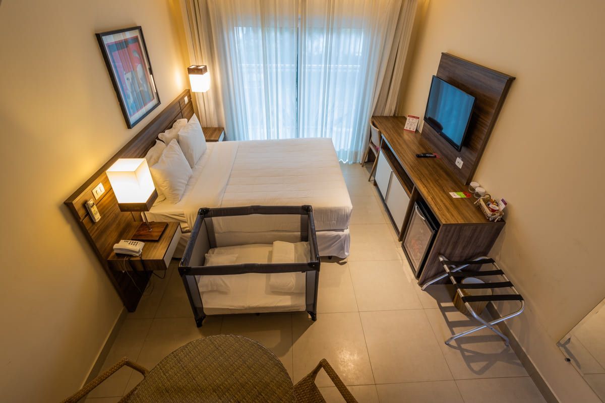 Um quarto de hotel com um berço e uma cama