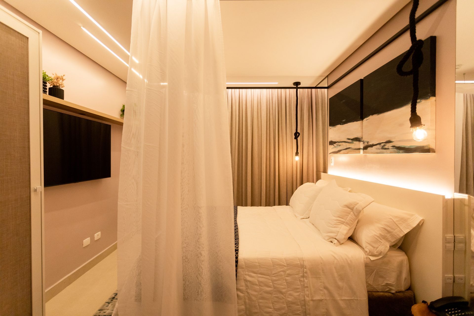 Um quarto com uma cama, televisão e cortinas.