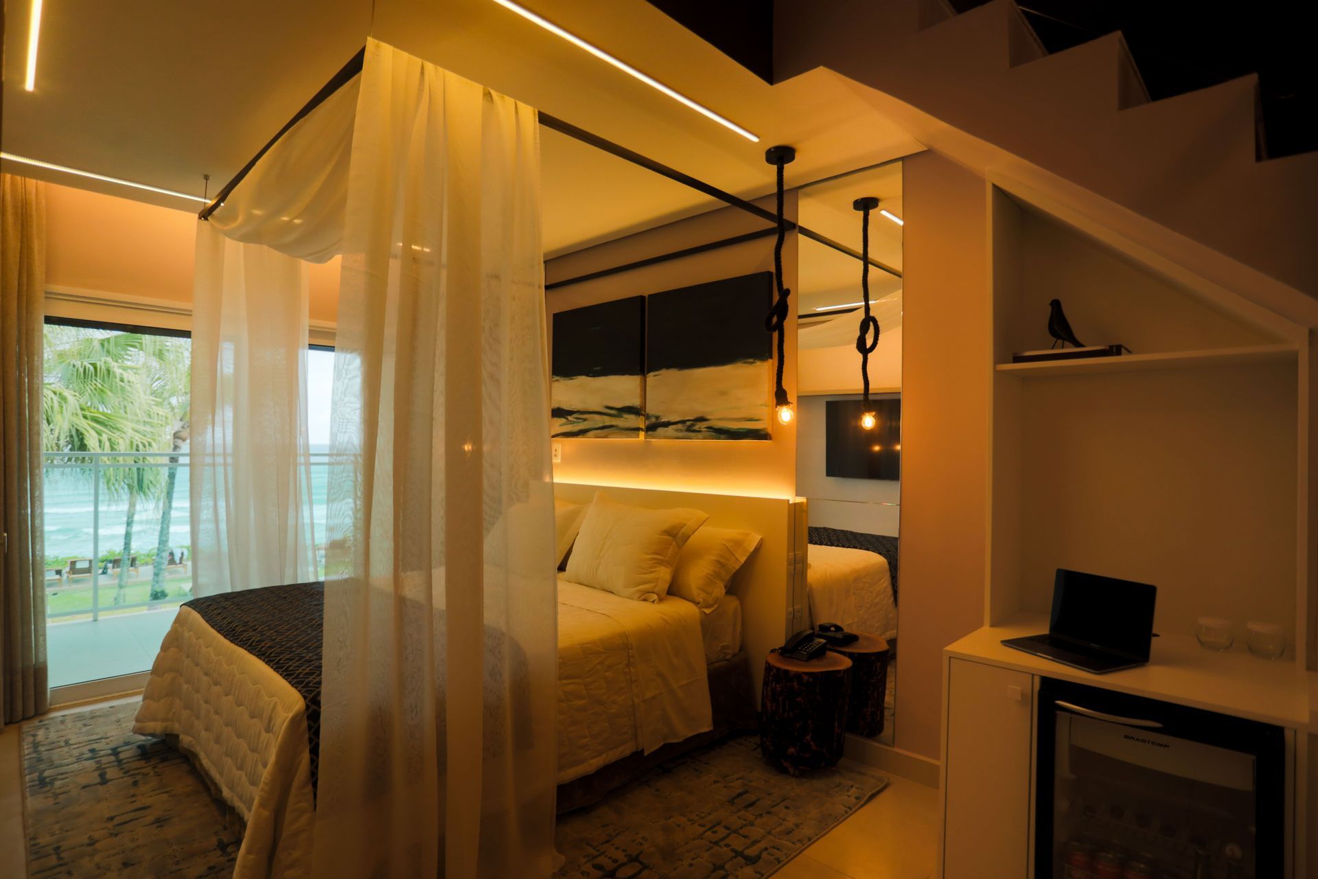 Um quarto com uma cama de dossel e um laptop em uma mesa