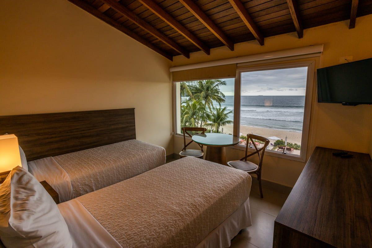 Um quarto de hotel com duas camas, uma mesa e uma televisão.