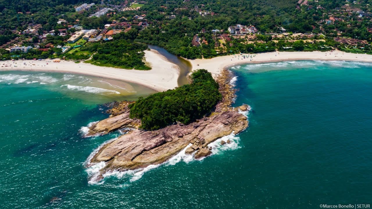Uma vista aérea de uma praia com montanhas ao fundo.