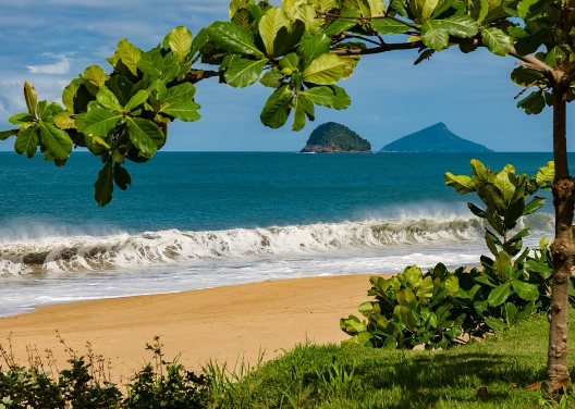 Uma vista aérea de uma praia com montanhas ao fundo.