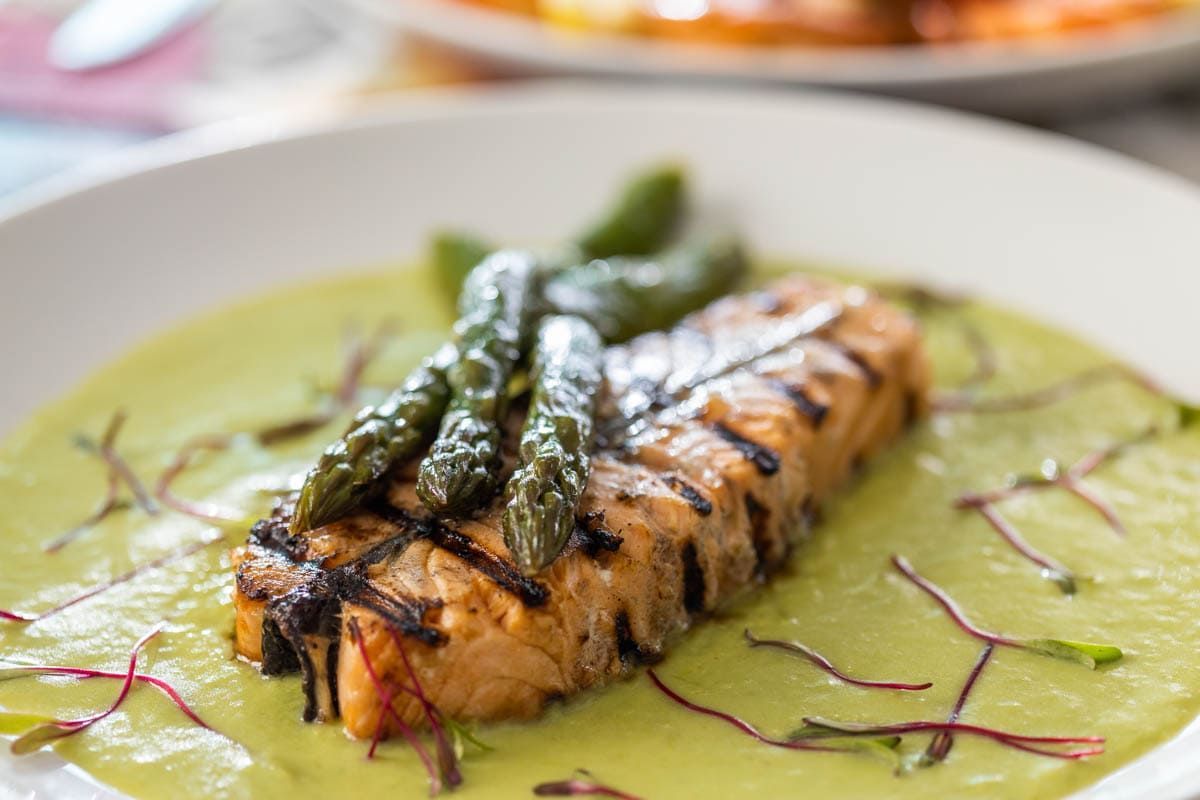 Um close de um prato de comida com aspargos e molho.