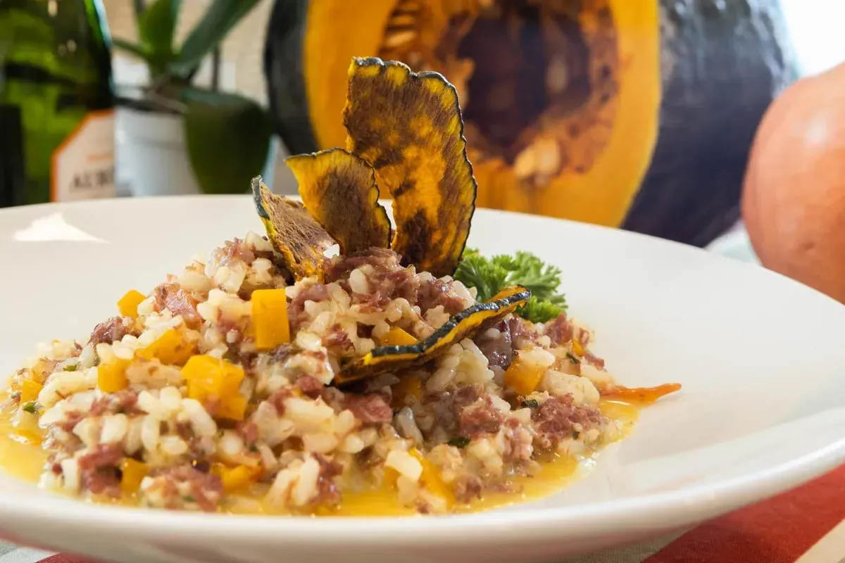 Um close de um prato de comida com uma abóbora ao fundo.