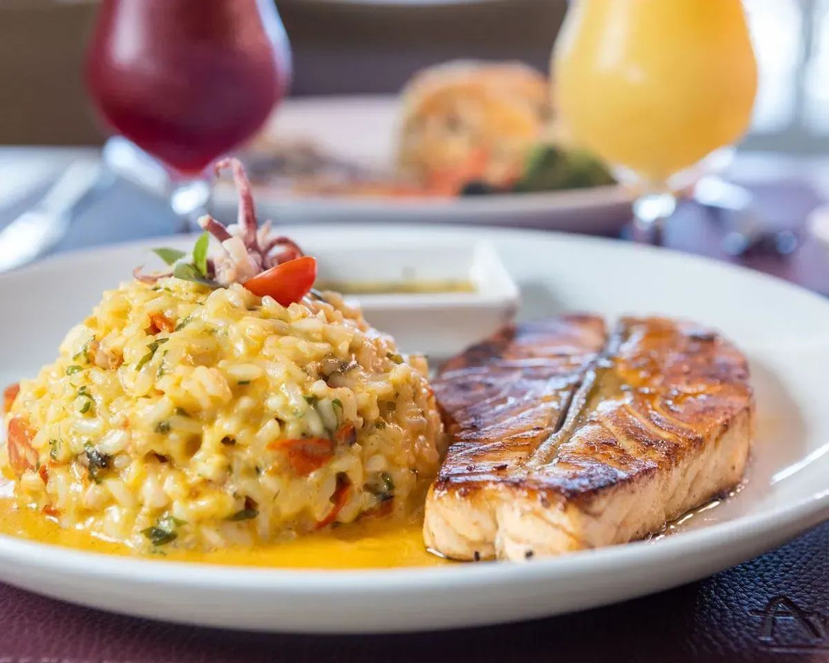 Um prato de comida com arroz e salmão sobre uma mesa.