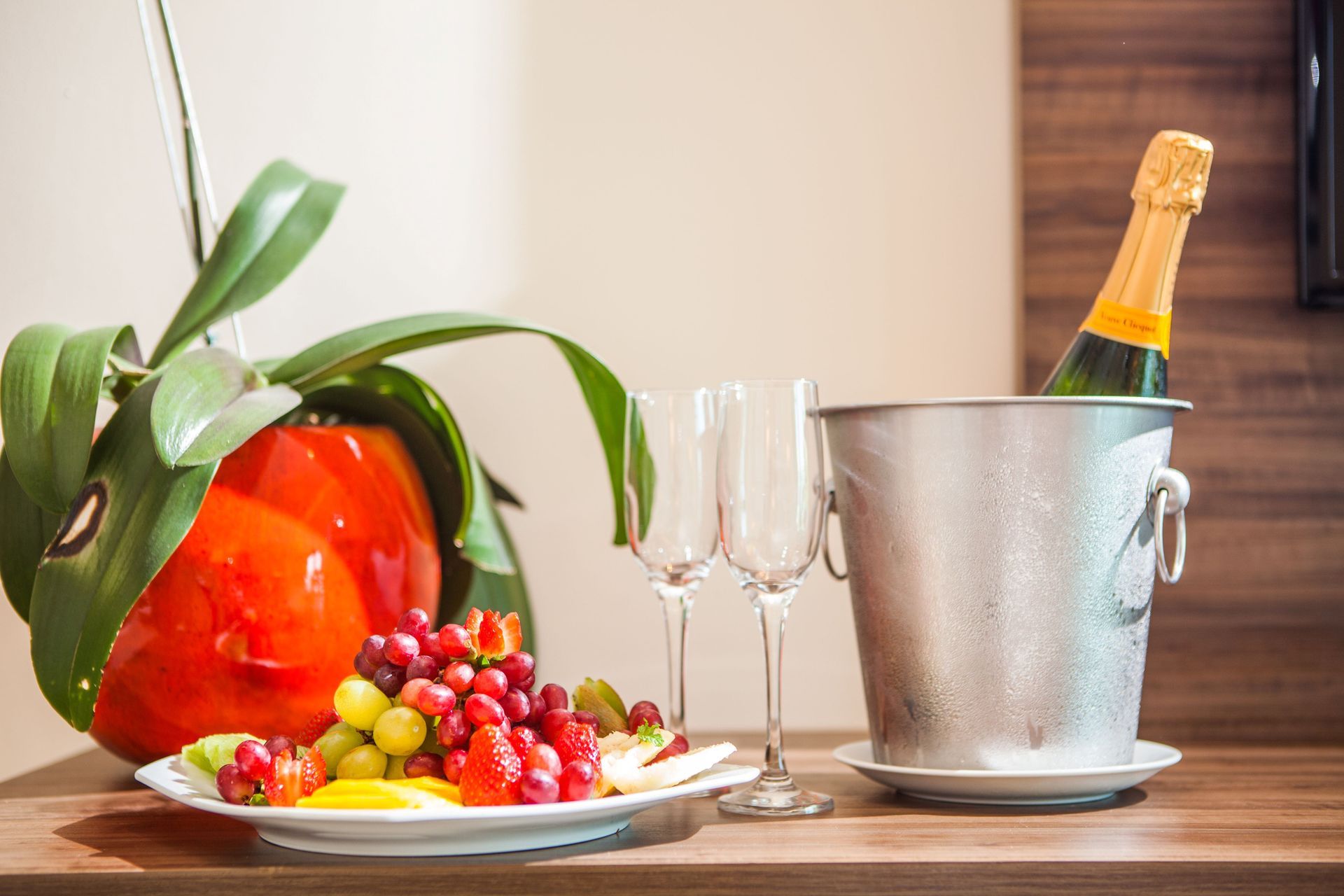 Há um prato de frutas e um balde de champanhe na mesa.