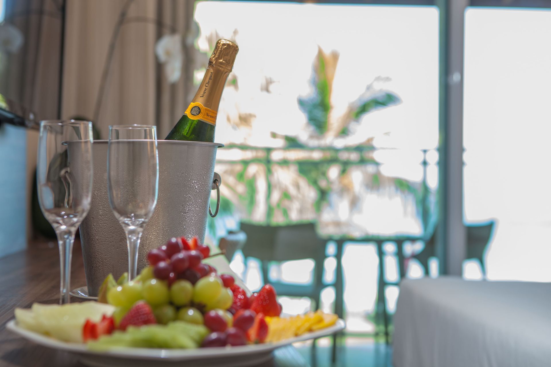 Uma garrafa de champanhe está em um balde ao lado de um prato de frutas.