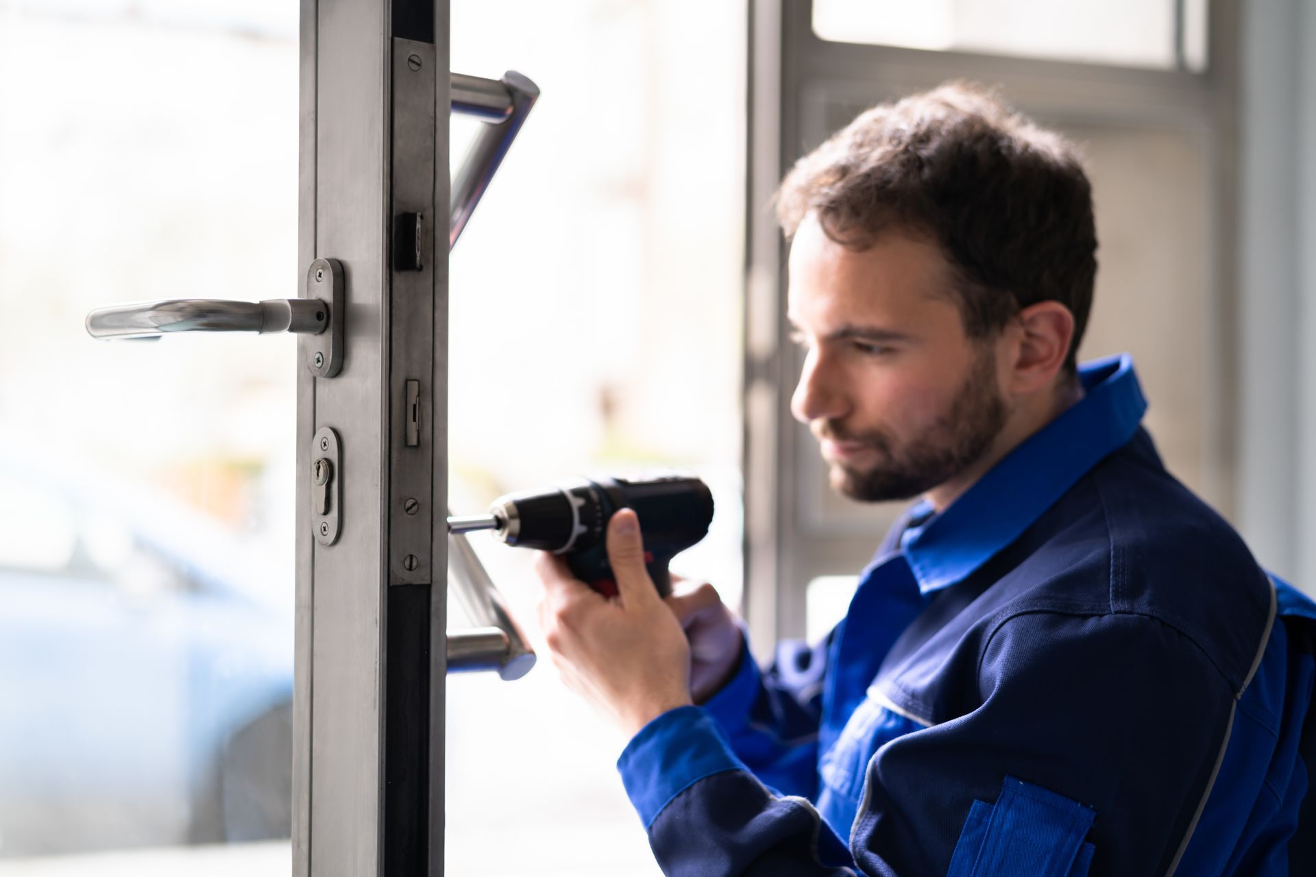 A professional locksmith installing a door lock for a local business.