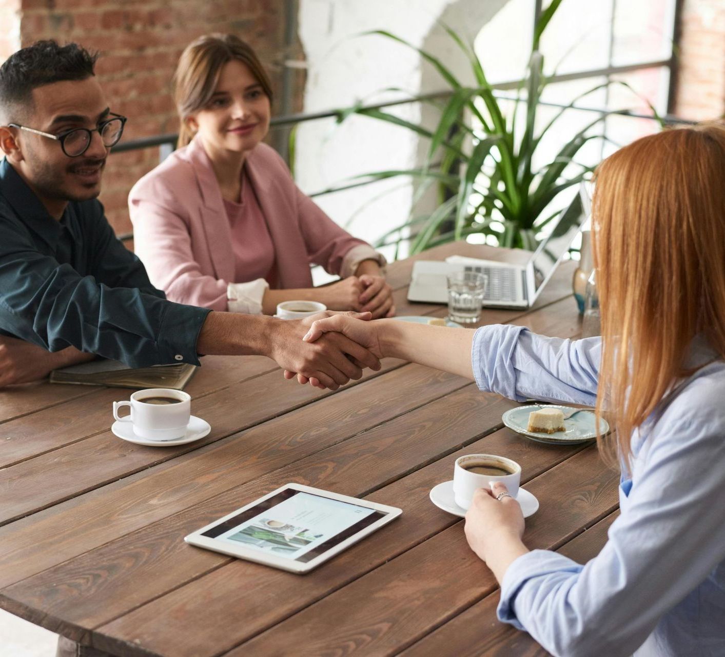 Tandem Growth.  A group of people are shaking hands over a wooden table.