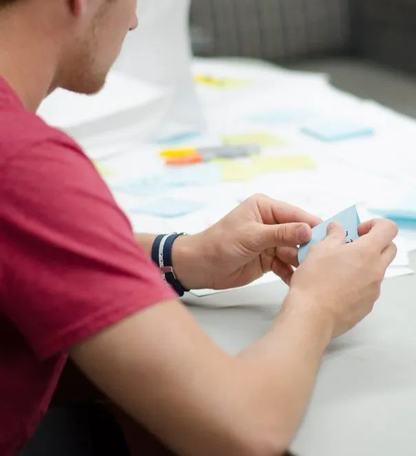 Tandem Growth.  A man in a red shirt is sitting at a table holding a piece of paper.