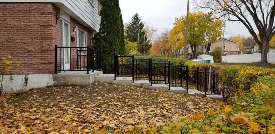 Une maison en briques avec une clôture et des escaliers devant.