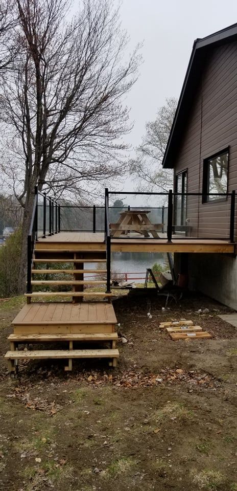 Une terrasse en bois avec des escaliers qui y mènent à côté d'une maison.