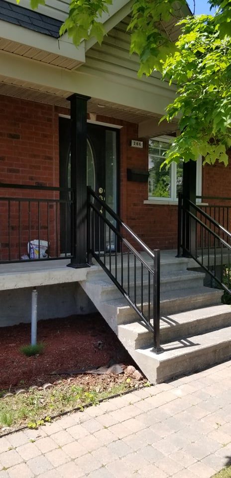Une maison en brique avec des escaliers et une rampe en fer forgé.