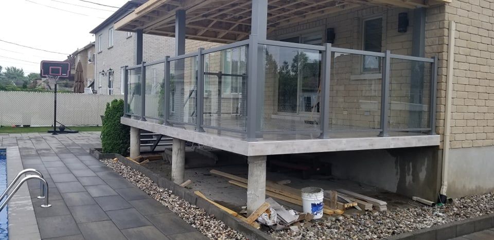 Une terrasse est en cours de construction dans l'arrière-cour d'une maison à côté d'une piscine.