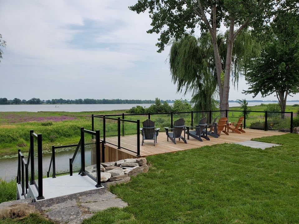 Une terrasse avec des chaises et des escaliers donnant sur un plan d'eau.