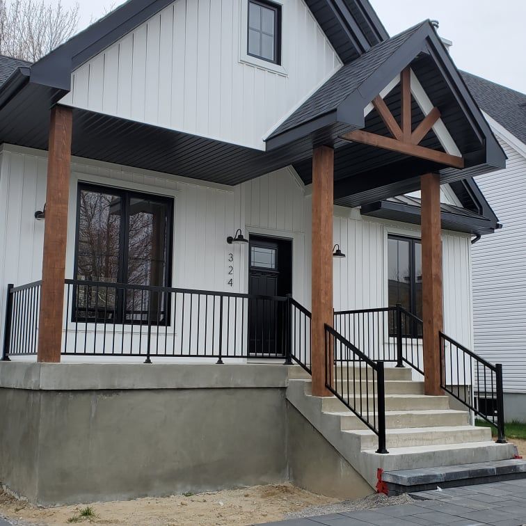 Une maison blanche avec un toit noir et des escaliers