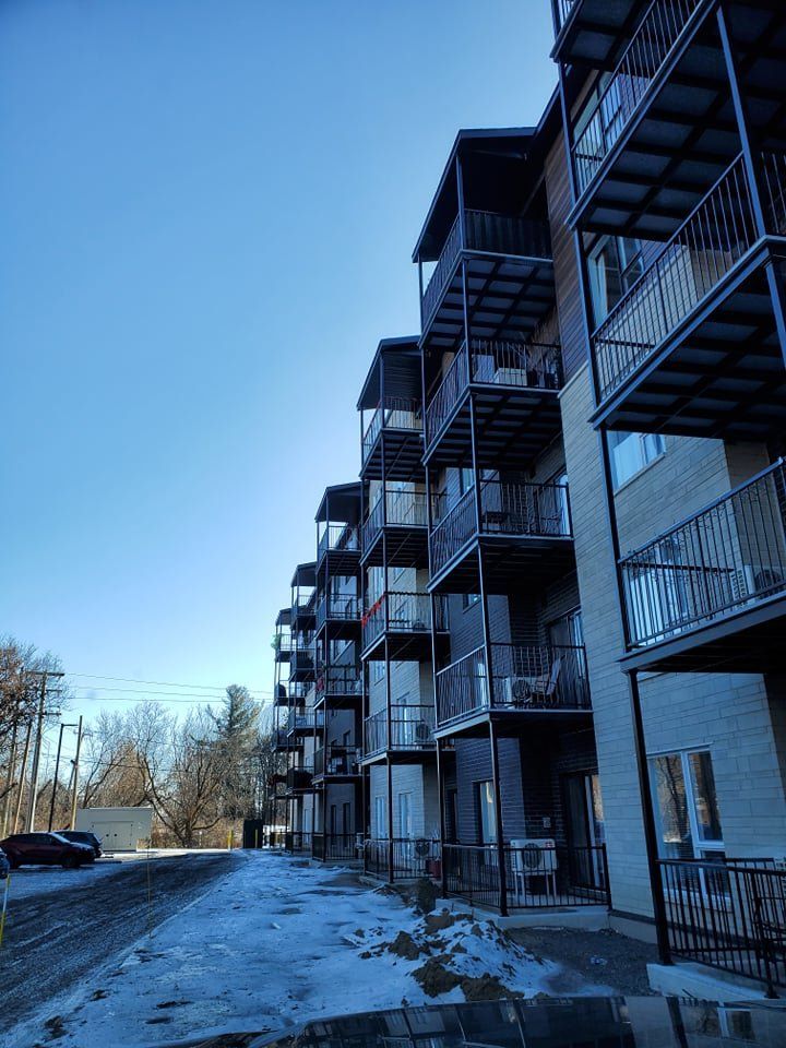 Un grand immeuble d'appartements avec beaucoup de balcons lors d'une journée ensoleillée.