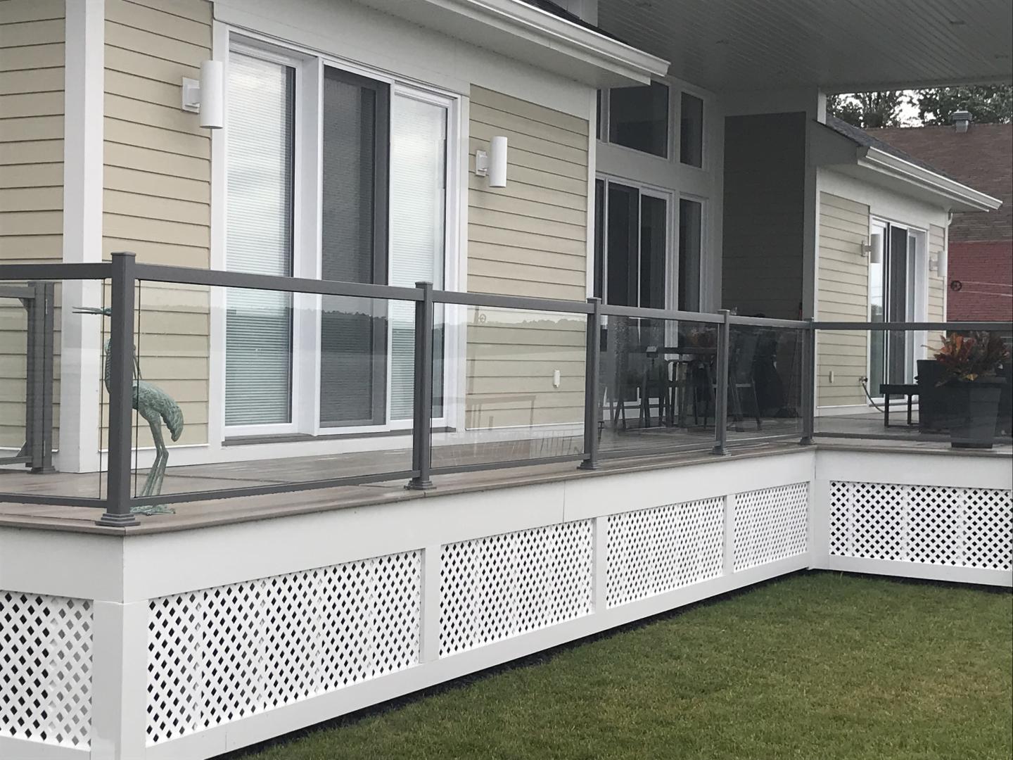 Une maison avec une balustrade en verre et une pelouse devant