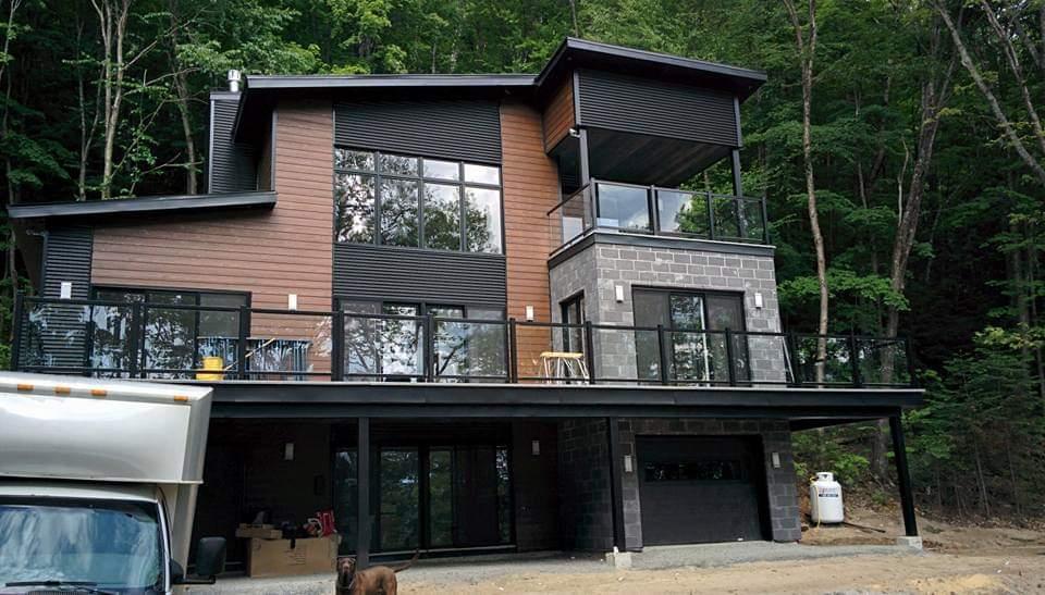 Une grande maison est située au sommet d'une colline au milieu d'une forêt.
