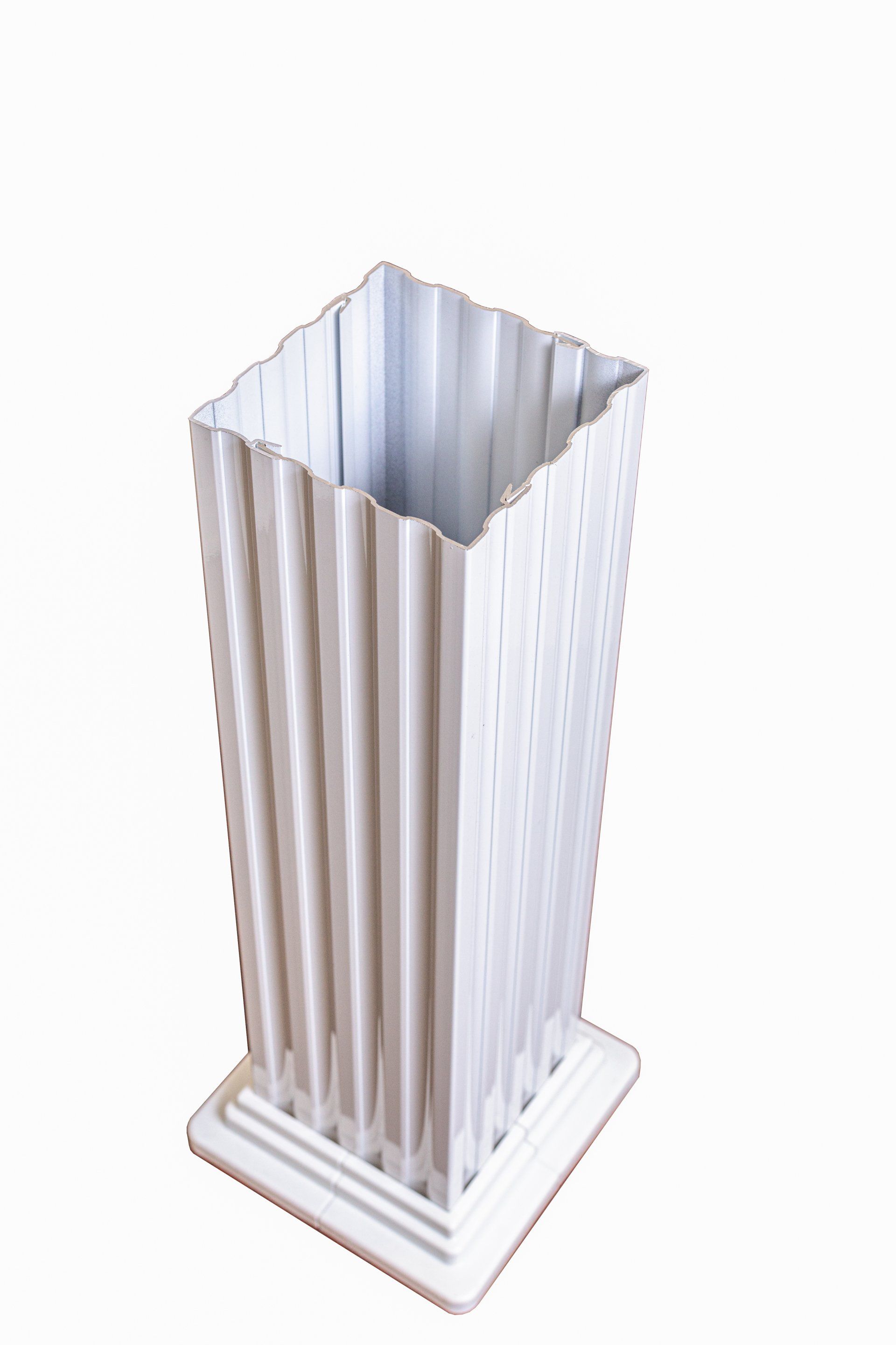 Un vase blanc est posé sur une base blanche sur un fond blanc.