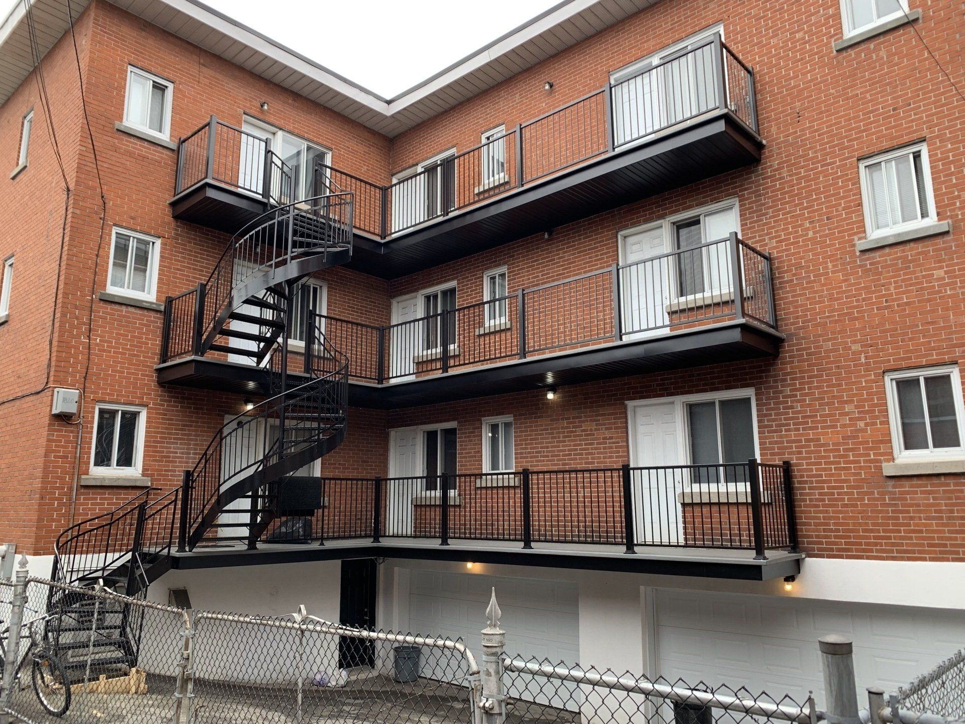 Immeuble d'appartements en briques rouges avec escaliers extérieurs en métal et balcons.