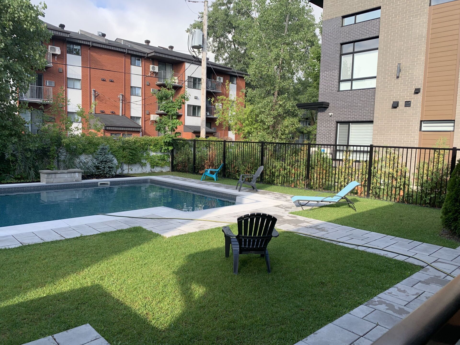 Une grande piscine est entourée d'une clôture et de chaises.
