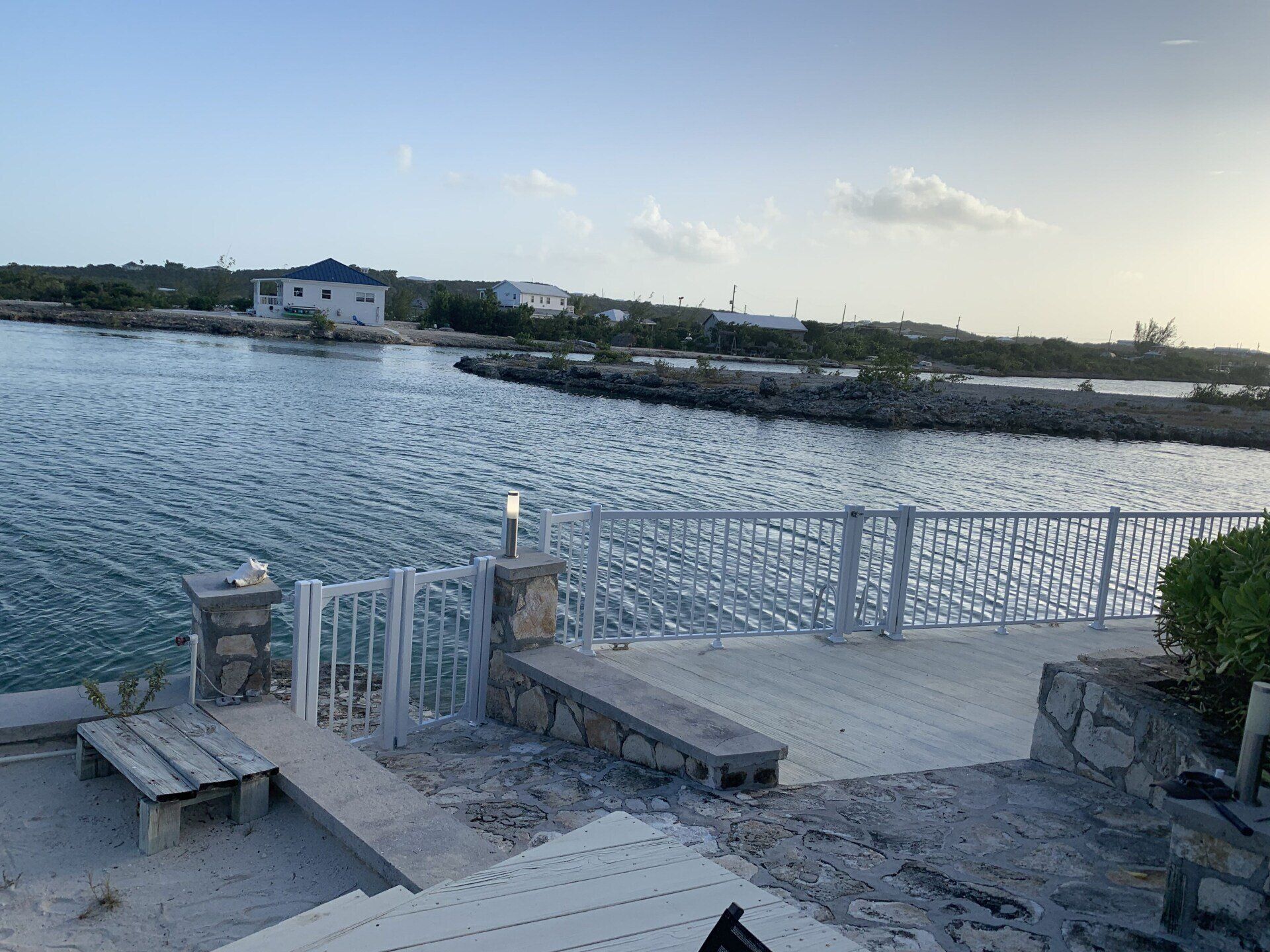 Un quai surplombant un plan d'eau avec une maison en arrière-plan.