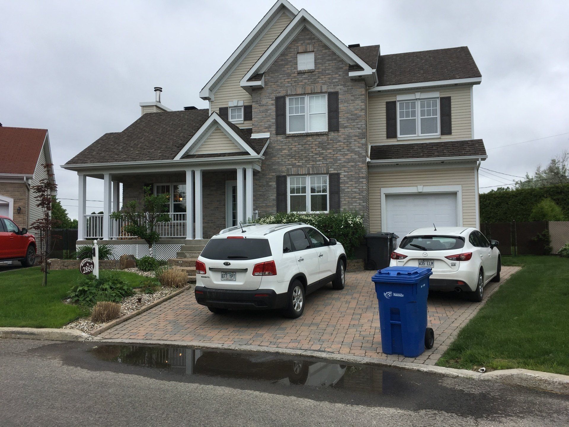 Deux voitures sont garées devant une grande maison.