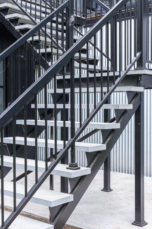 Un ensemble d'escaliers avec une rampe en métal menant à un bâtiment.