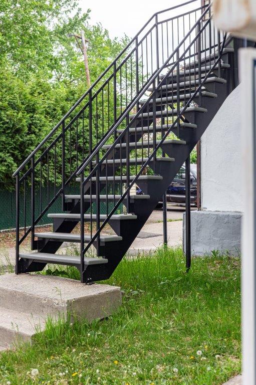Un ensemble d'escaliers avec une rampe en métal menant à un bâtiment.