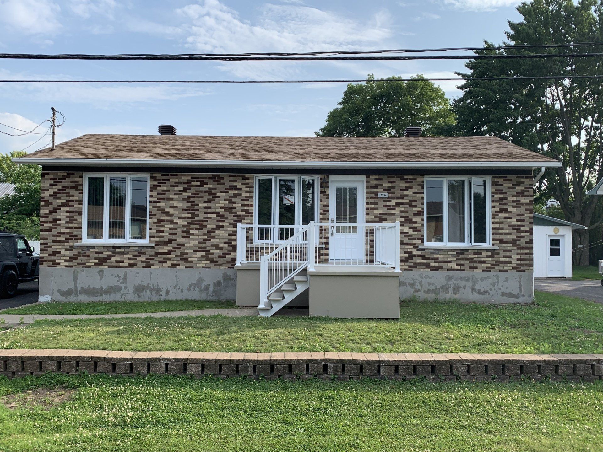 Une petite maison en briques avec une voiture garée devant.