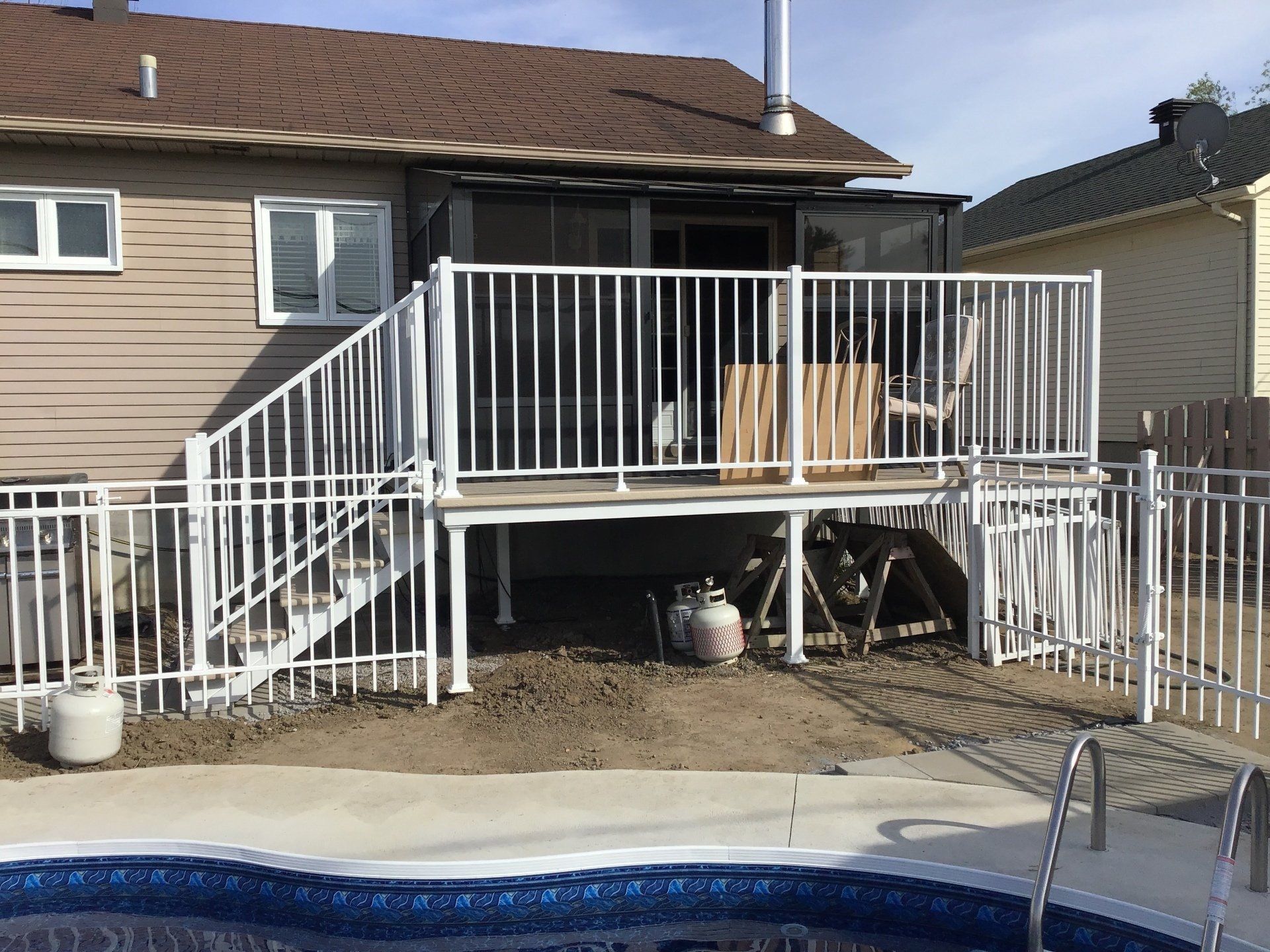 Une maison avec une terrasse et des escaliers à côté d'une piscine.