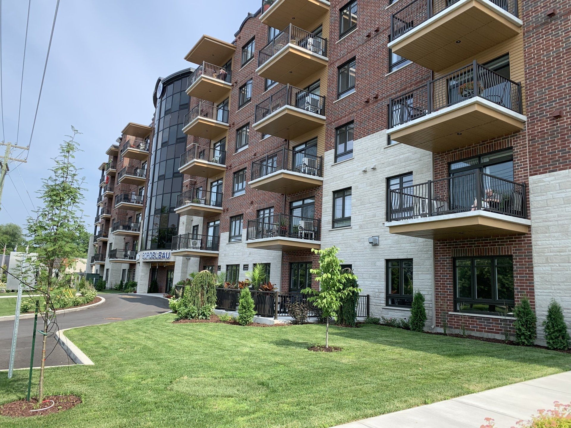Un grand immeuble d'appartements avec des balcons et une pelouse verte luxuriante devant lui.