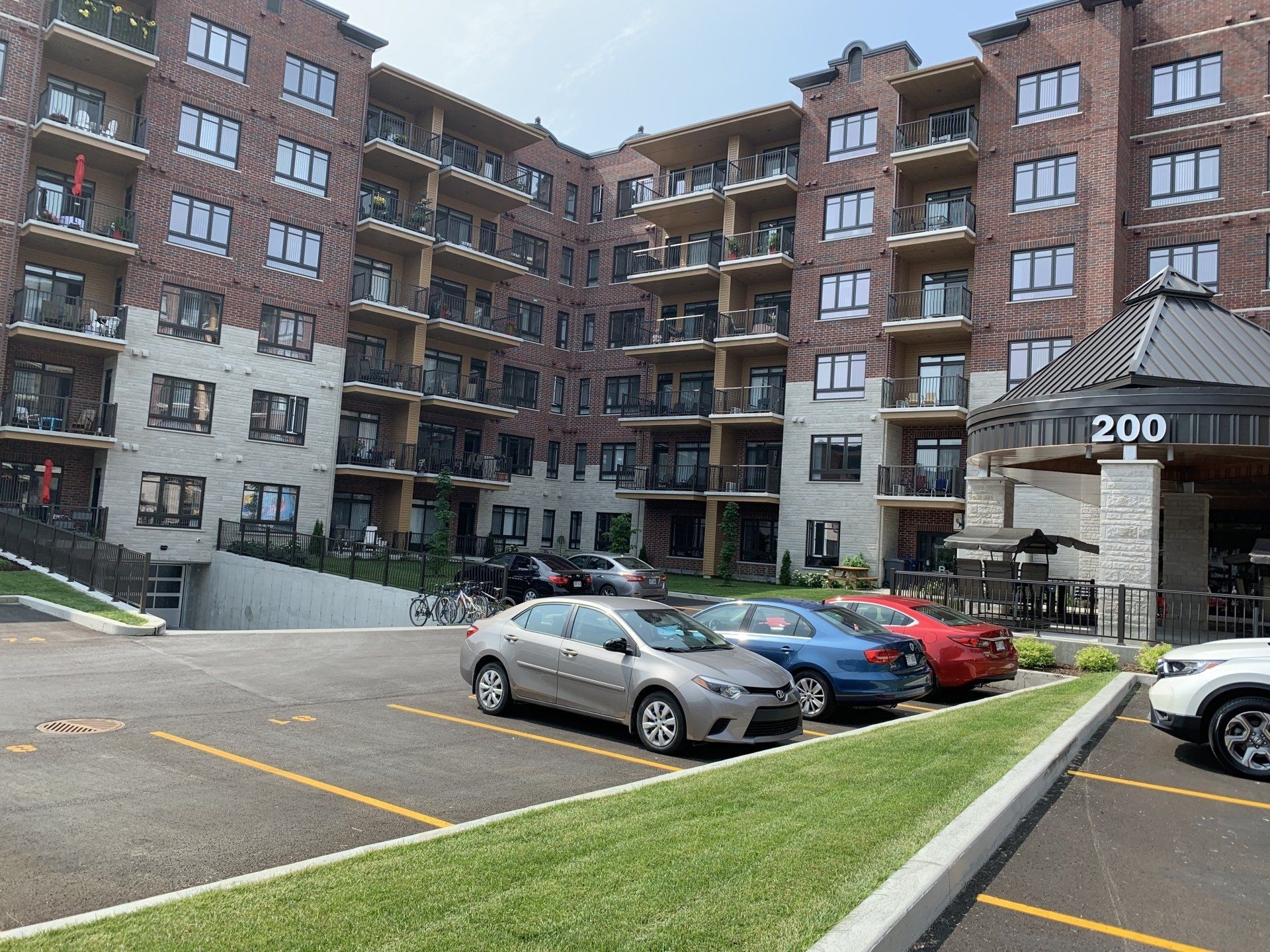 Un parking devant un grand immeuble d'appartements avec des voitures garées devant.
