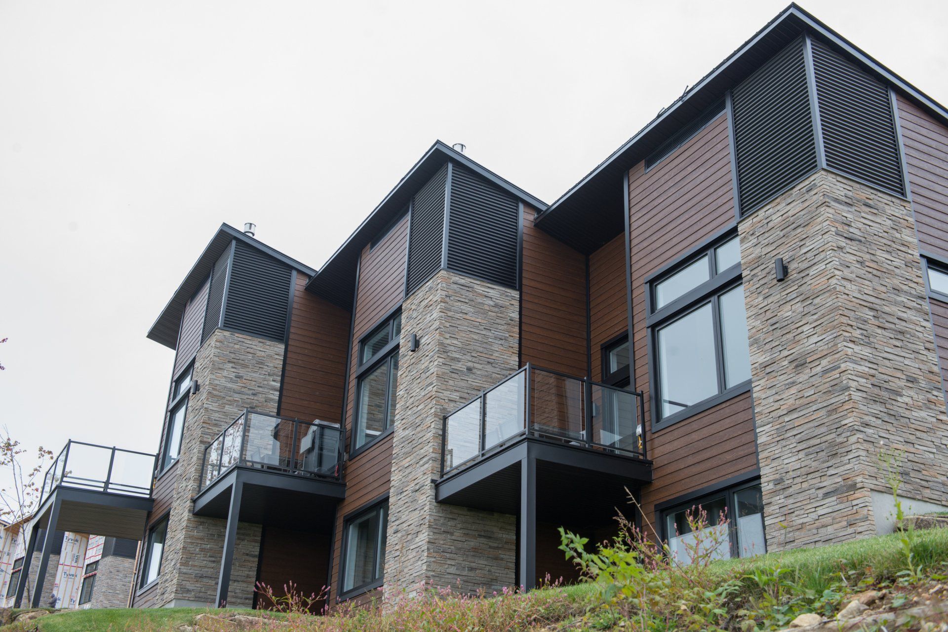 Une grande maison avec beaucoup de fenêtres et de balcons est située au sommet d'une colline.