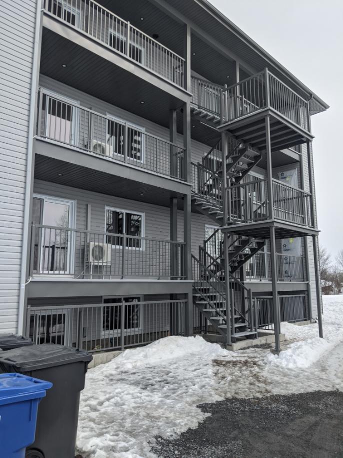 Un bâtiment avec des escaliers et des balcons est recouvert de neige.