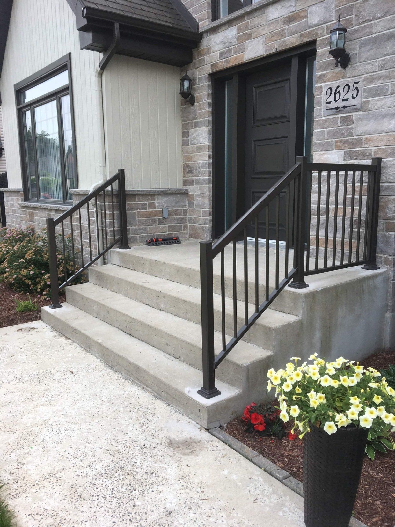 Il y a un pot de fleurs devant l'escalier d'une maison.