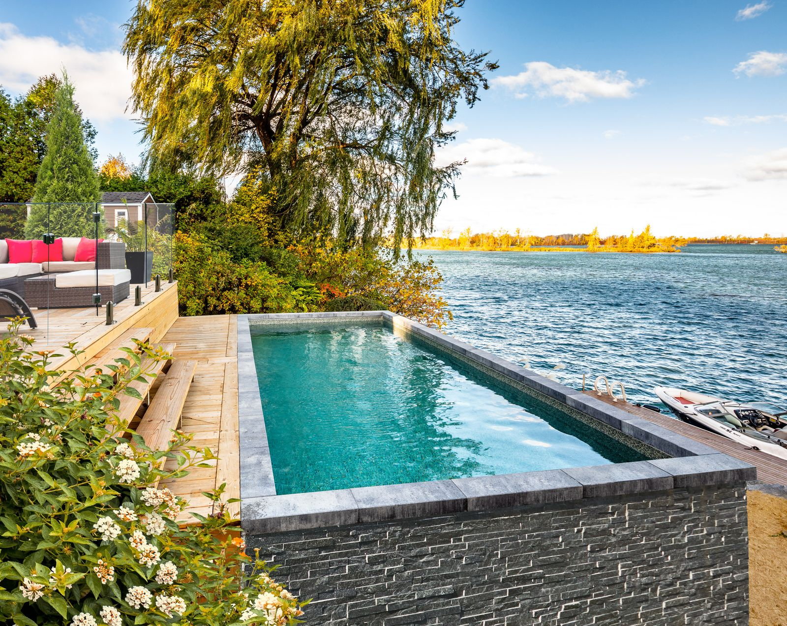 Pool with lit gazebo featuring a stone fireplace, seating, and a wooden frame.