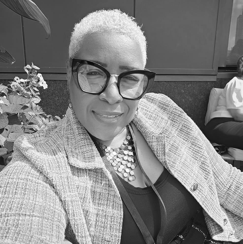 A black and white photo of a woman wearing glasses and a necklace.