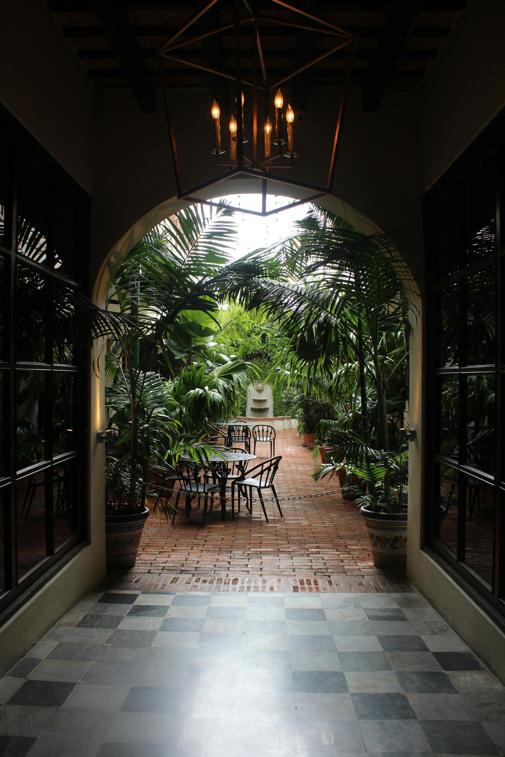 A hallway leading to a garden with tables and chairs