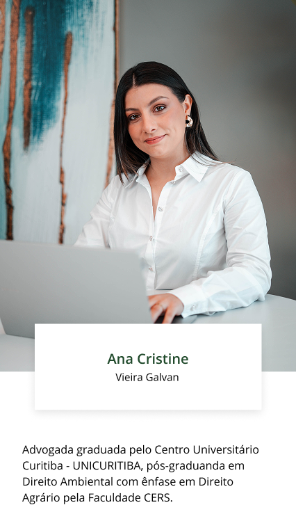 Uma mulher de camisa branca está sentada em uma mesa com um laptop.